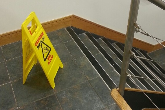 Clean communal stairwell with stainless steel handrails and a caution sign
